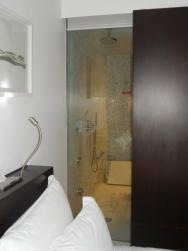 prosklená stěna z pokoje do koupelny (lze zatáhnout roletu nebo posunout posuvné dveře od skříně - tím pádem otevřete ale skříň)