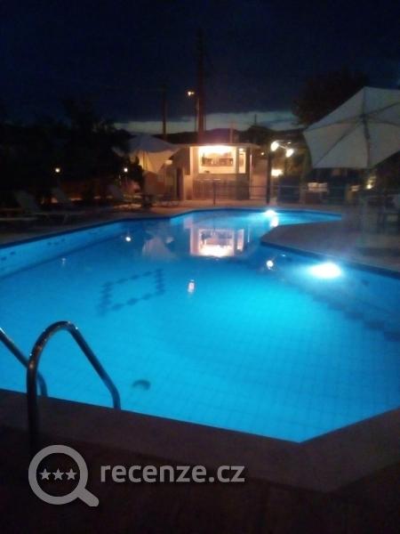 Osvětlený bazén a bar v noci.